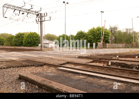 Railway Level Crossing in the UK with electrified cables on gantry overhead Stock Photo