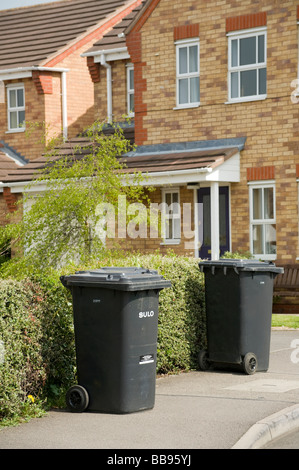 Black rubbish wheelie bins waiting to be collected on a street in England Stock Photo