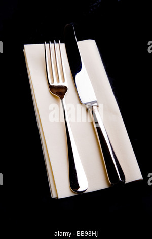 Silver plated knife and fork on a cream paper table napkin Stock Photo