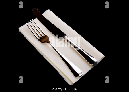 Silver plated knife and fork on a cream paper table napkin Stock Photo