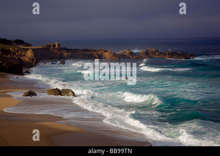 Garrapata State Park CA Light breaking through morning cloud cover onto beach and breaking waves Stock Photo