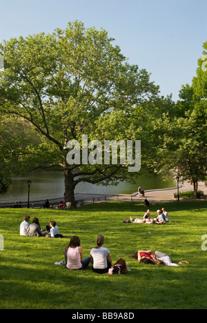 People Relaxing on the lawn by the Conservatory Water Pond in Central Park New York City Stock Photo