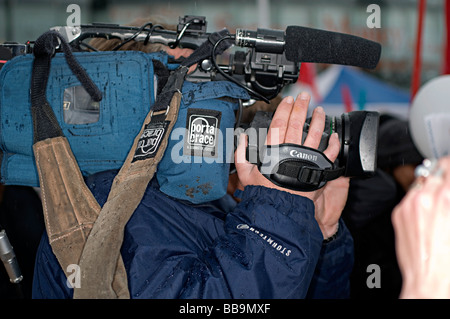 a camera man journalist and news gatherer filming in the rain Stock Photo