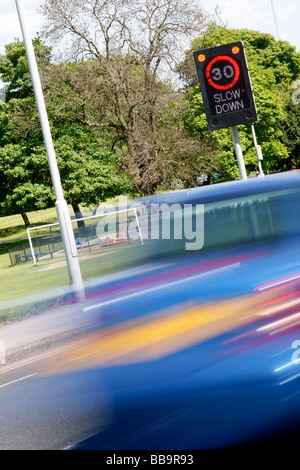 Illuminated 30 limit slow down sign at side of road Stock Photo - Alamy