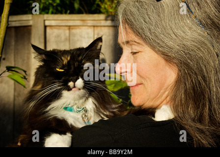 Woman cuddling crabby longhaired Norwegian Forest cat Stock Photo