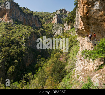 Walkers on a narrow path in the Apothetes ravine, Langadhiotissa gorge, Taygetos mountains, near Mystras, Peloponnese, Greece Stock Photo