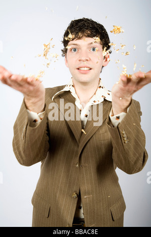 A young man tossing gold foil in the air Stock Photo