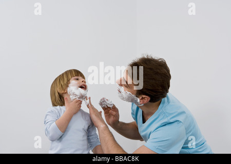 A father applying shaving cream to his young son Stock Photo