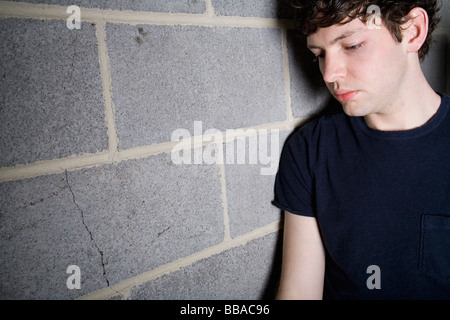 A young man leaning against a brick wall Stock Photo