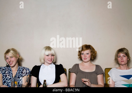 Four young woman sitting against a wall in a bar Stock Photo