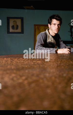 A young man sitting at a bar counter with a drink Stock Photo