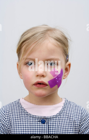 A young girl with a adhesive bandage on her cheek Stock Photo