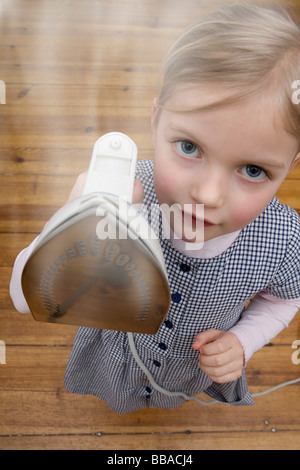 A young girl holding up a steaming hot iron Stock Photo