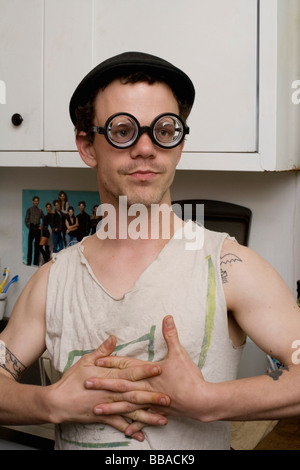 A young man standing in a kitchen wearing silly glasses Stock Photo