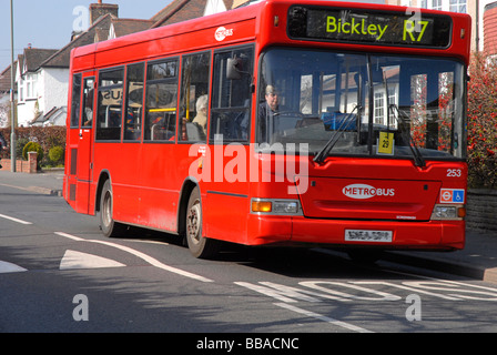 Single deck red bus on speed hump Stock Photo