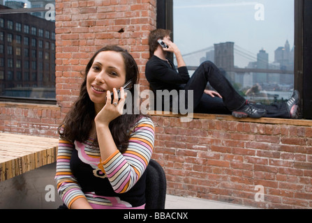 Two people talking on mobile phones in a modern apartment Stock Photo