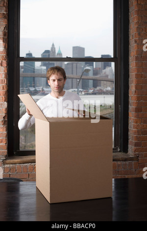 Man unpacking cardboard box in office Stock Photo