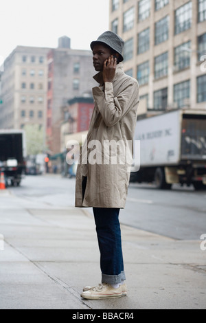 A young man standing on a sidewalk and using a mobile phone Stock Photo