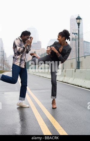 A man and a woman standing on a street and play fighting Stock Photo