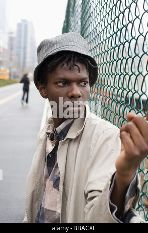 A young man leaning against a chainlink fence Stock Photo