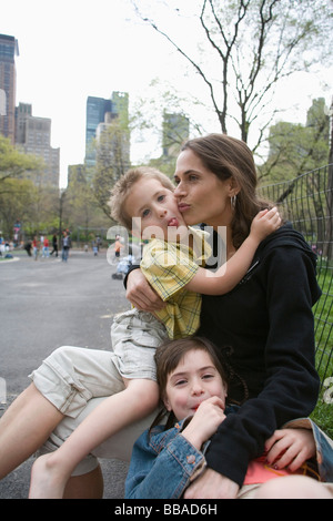 A mother sitting with her children in Central Park, New York City Stock Photo