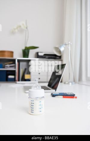 A baby's bottle on an office desk Stock Photo