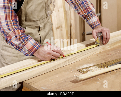 Detail of man marking piece of timber using pencil and tape measure Stock Photo