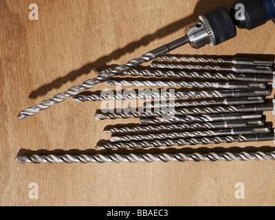 A drill and assorted drill bits on a bench Stock Photo