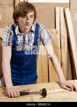 A young man leaning on a bench in a wood workshop Stock Photo