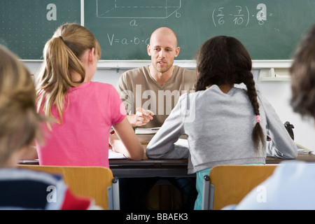 A teacher talking to students in a classroom Stock Photo