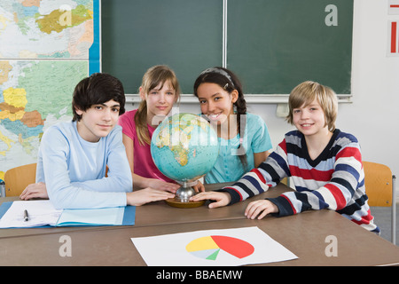 School students sitting at a table with a world globe Stock Photo