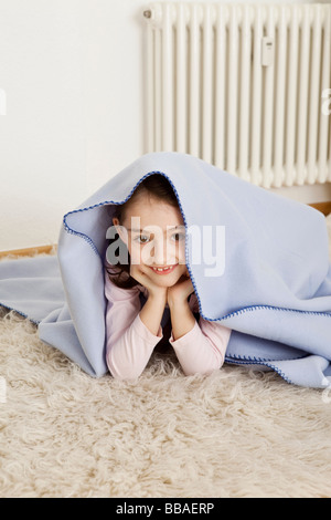 A young girl hiding under a blanket Stock Photo