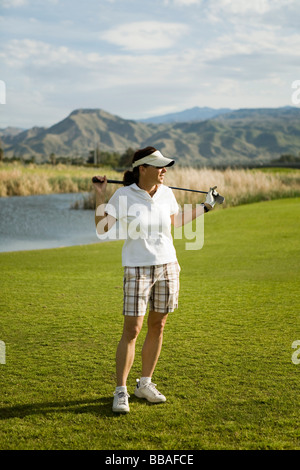 A golfer standing with golf clubs across her shoulders, Palm Springs, California, USA Stock Photo