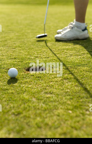 Detail of a golf ball next to a hole Stock Photo