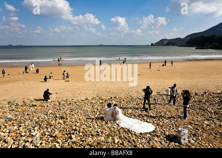 China, Zhejiang Prefecture, Zhoushan Island, beach with wedding couples and surfers Stock Photo