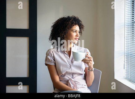 Young woman with cup, thinking Stock Photo