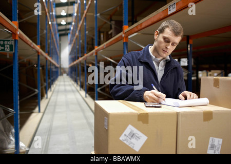 Worker filling in paperwork in warehouse Stock Photo