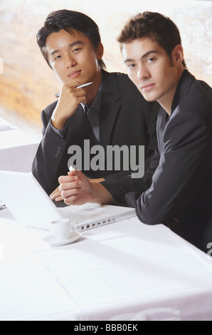 Two men sitting in restaurant with laptop, working Stock Photo