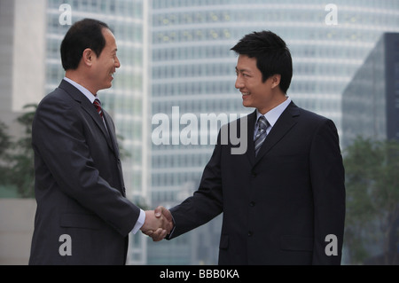Two Chinese businessmen shake hands in China Stock Photo