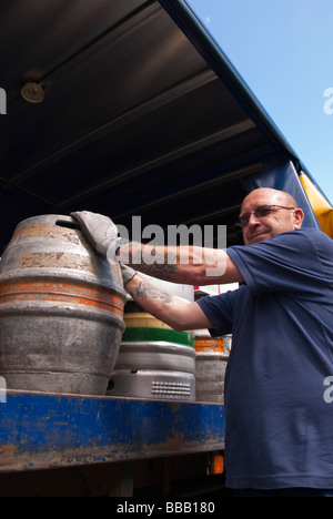 An Adnams brewery staff worker unloading and delivering ale and beer to a pub from the back of a lorry in Suffolk,Uk Stock Photo