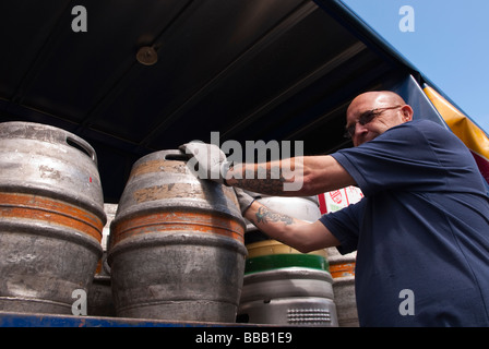 An Adnams brewery staff worker unloading and delivering ale and beer to a pub from the back of a lorry in Suffolk,Uk Stock Photo