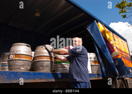 An Adnams brewery staff worker unloading and delivering ale and beer to a pub from the back of a lorry in Suffolk,Uk Stock Photo