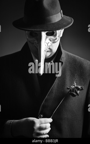 A black-and-white portrait of a man with a Venetian carnival mask Stock Photo