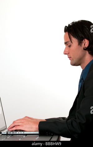 Young businessman sitting and typing on laptop keyboard on white background Stock Photo