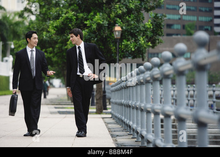 Two businessmen walking side by side, talking Stock Photo - Alamy