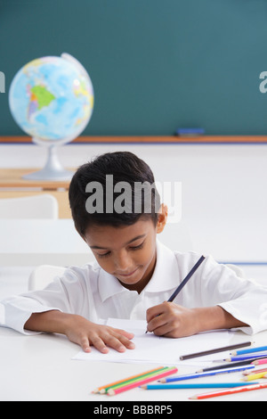 boy at desk with colored pencils Stock Photo