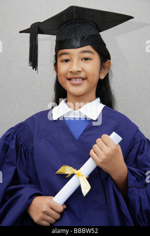 Indian girl holding a diploma wearing a graduation gown and cap. Stock Photo