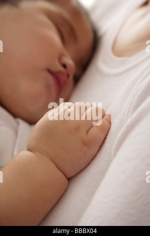 baby girl sleeping against woman's chest Stock Photo