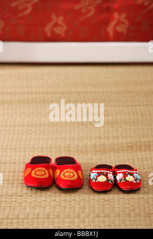 Still life of 2 pairs of red shoes on weaved mat Stock Photo