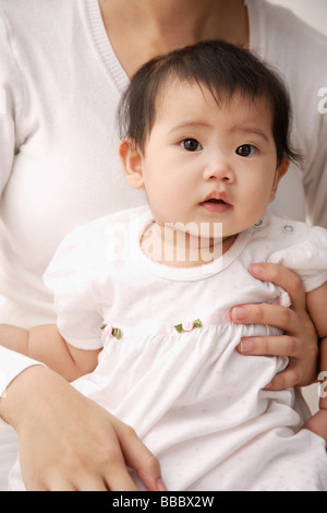 Baby girl being held on woman's lap Stock Photo